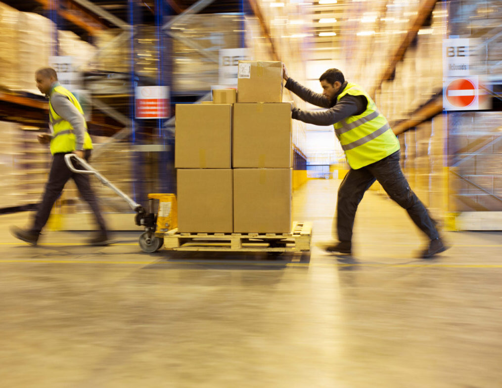 Workers carting boxes in warehouse