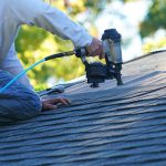 handyman using nail gun to install shingle to repair roof