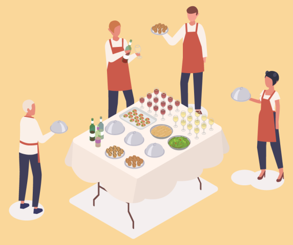 Caterers standing around a table of food with serving platters.