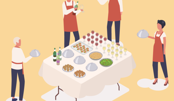 Caterers standing around a table of food with serving platters.